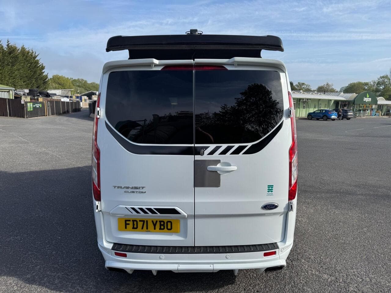 The rear of a HubDub-converted Ford Transit Custom with its pop top raised, photographed at the workshop