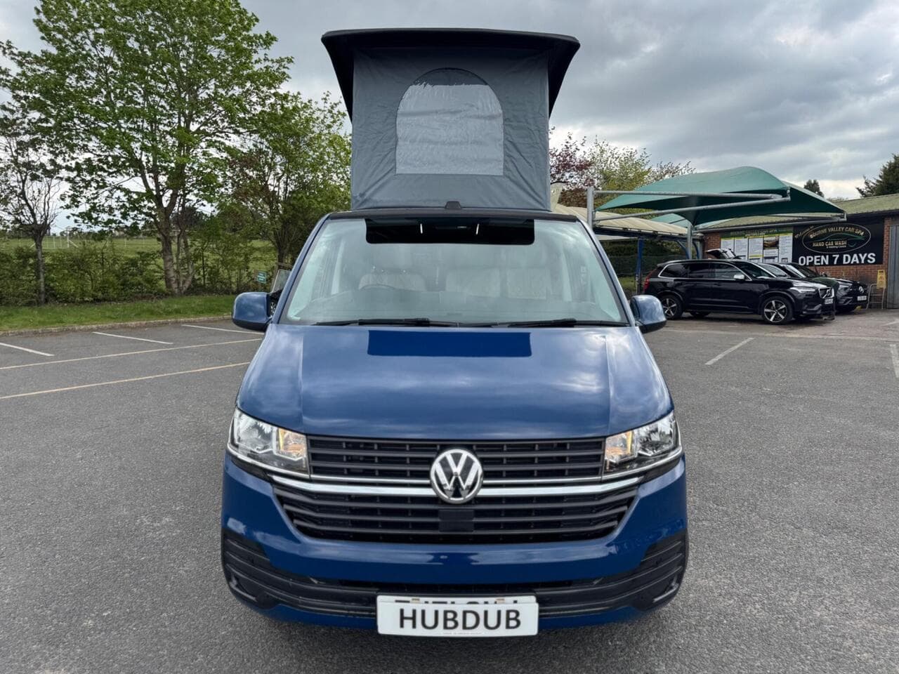 A HubDub-converted VW Transporter with its pop top raised, photographed head-on at the workshop