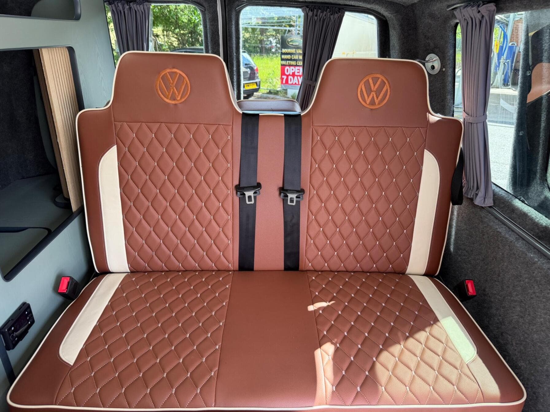 M1 crash-tested rock and roll bed in quilted rust leather with cream inserts, embroidered VW roundels and three-point seatbelts