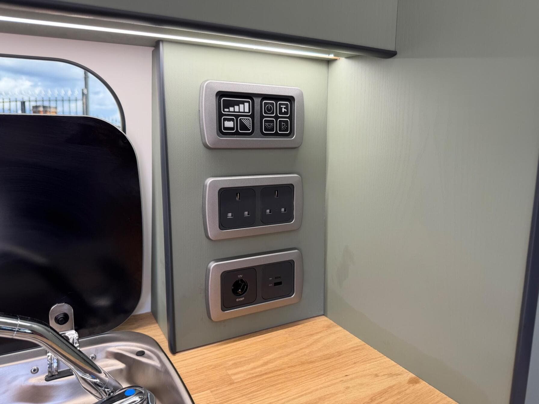 Control panel in a HubDub campervan with battery and solar readout, two UK three-pin sockets, a 12V outlet and USB-A and USB-C charging points