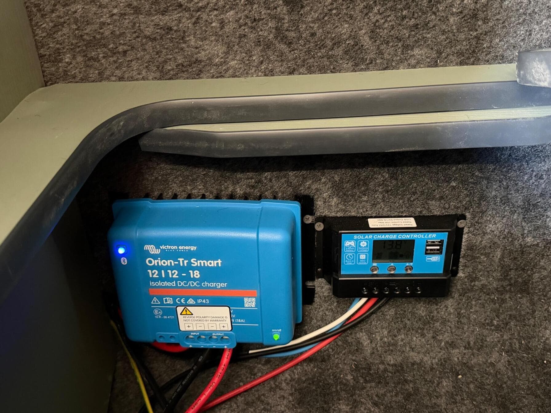 Victron Energy Orion-Tr Smart 12 to 12 volt 18 amp DC to DC charger and a solar charge controller mounted under the bench seat, wired in red and black cable