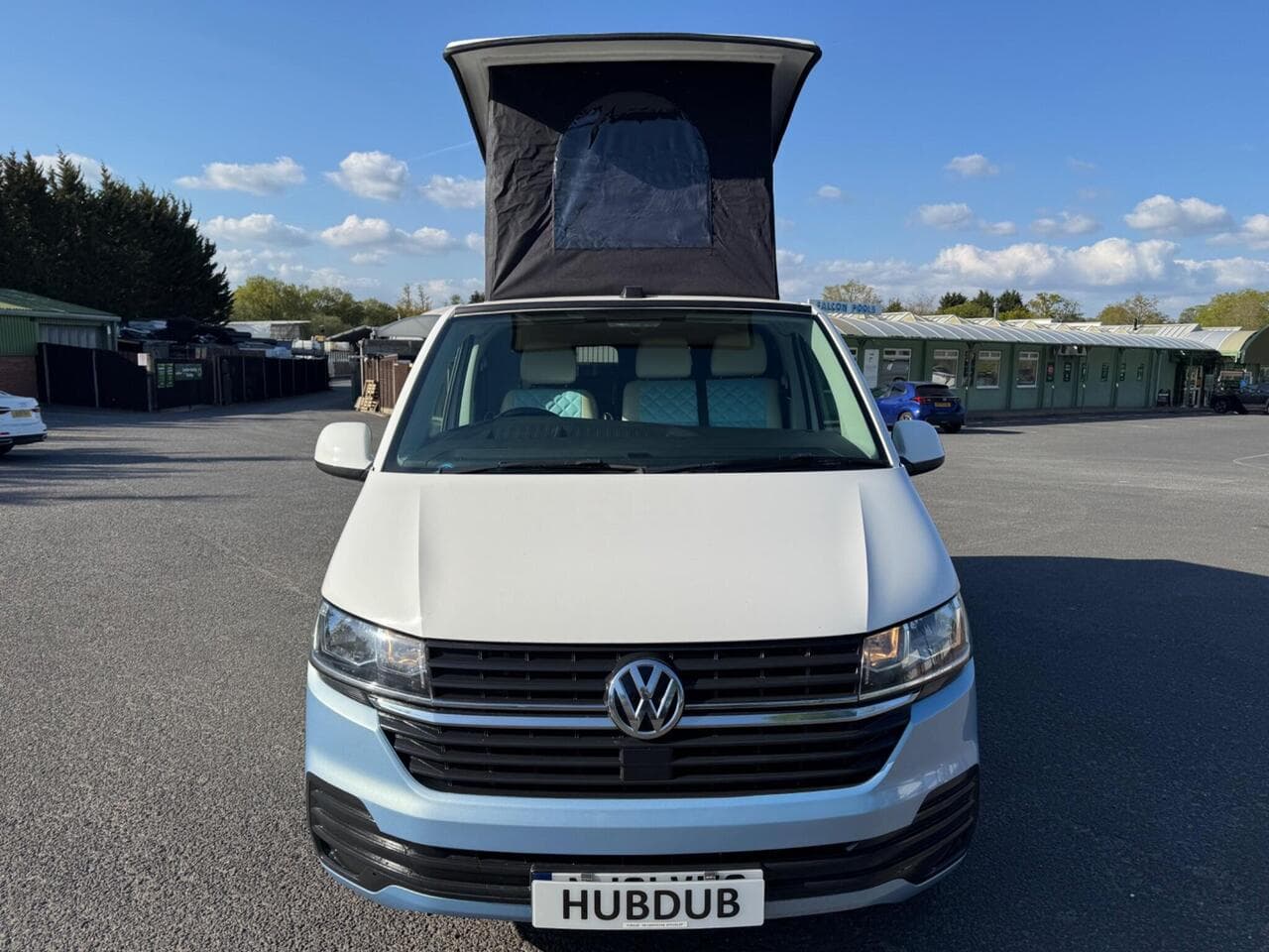 A HubDub-converted VW Transporter T6.1 with its gloss black pop top raised, photographed on the forecourt at Petersfield