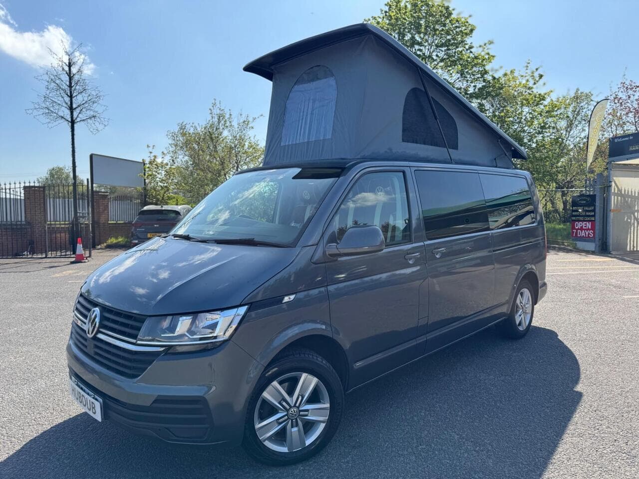 A HubDub-converted VW Transporter with its pop top raised, photographed three-quarter front